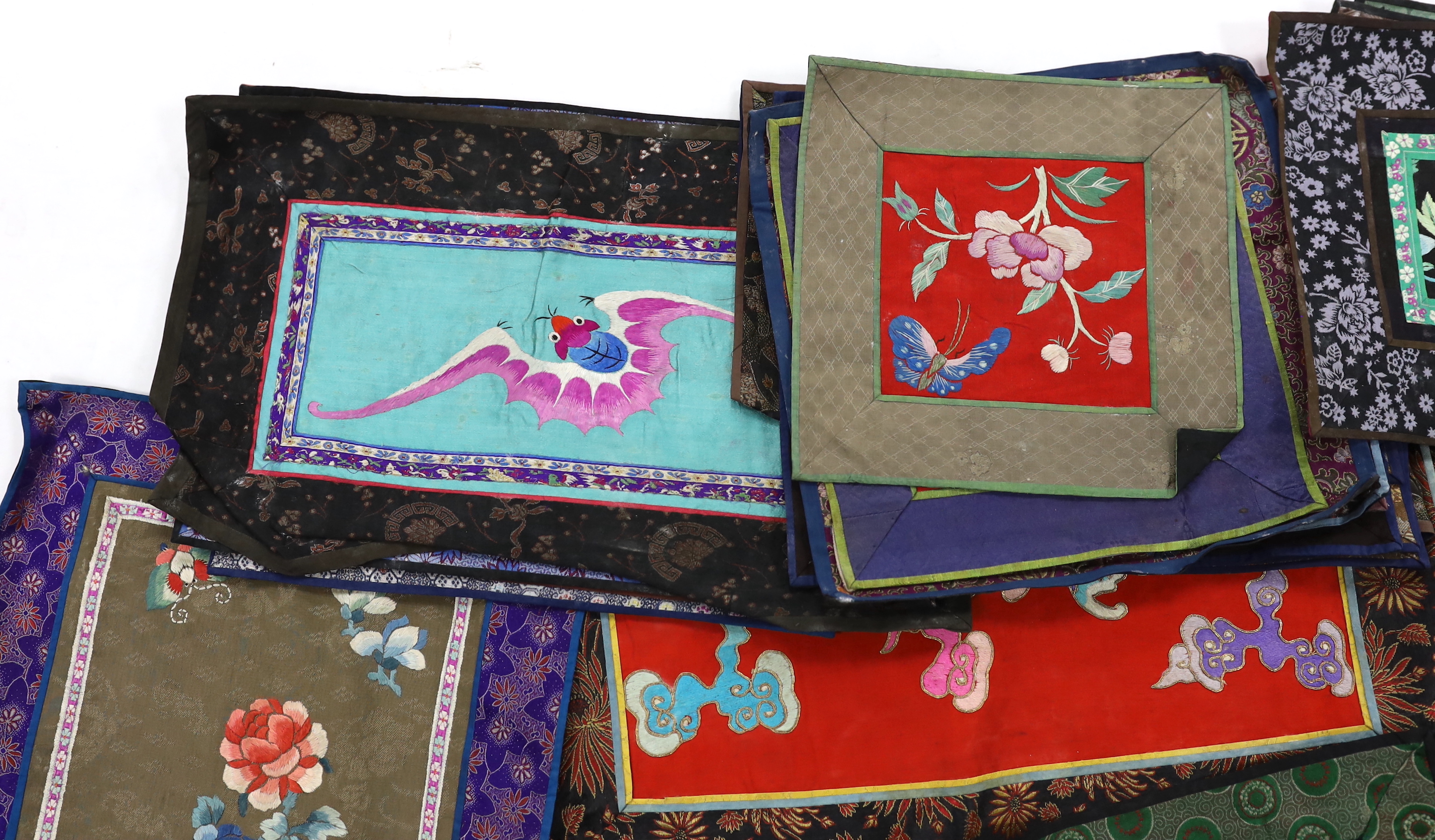 Twenty six assorted Chinese polychrome silk embroidered mats with silk damask borders of varying sizes